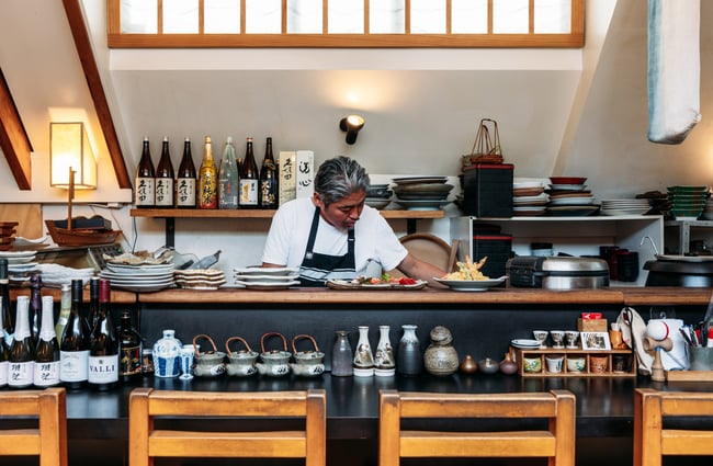 A chef with his head down, working in a kitchen.