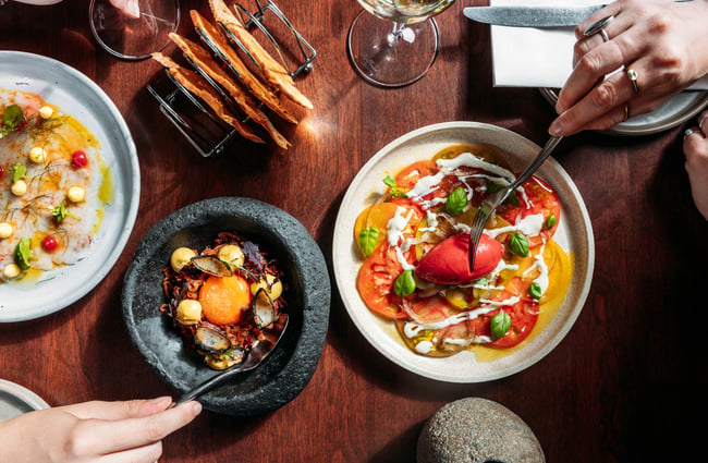 Birdseye view of three elegantly presented dishes on a tabletop.
