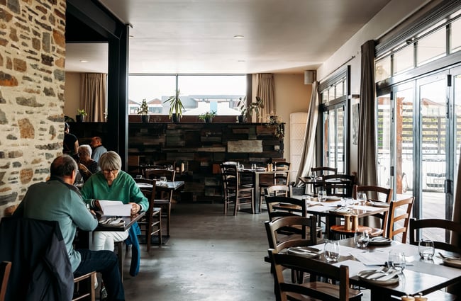 Interior dining area of kika where some customers are reading a menu seated at a table.