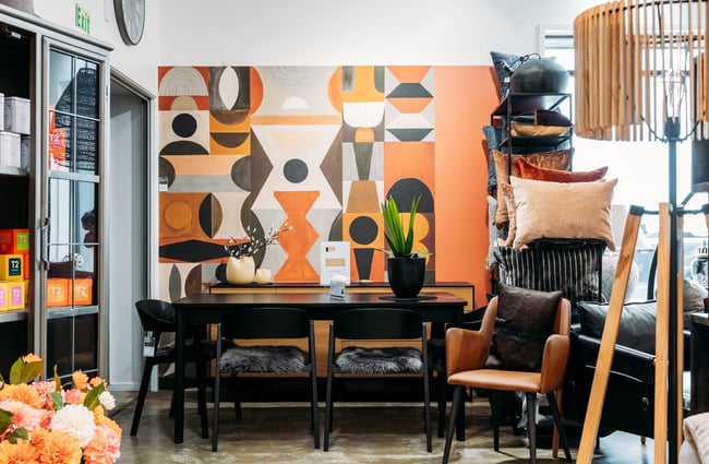 Large colourful artwork behind dining table and chairs at King & Teppett.