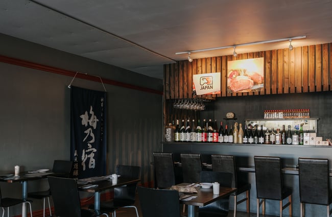The interior of the Kinji Japanese restaurant with dark moody lighting.