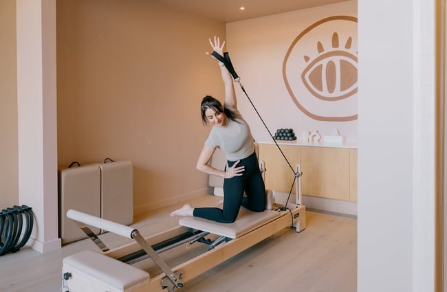 Reformer pilates instructor demonstrating move on reformer at Kula Studio in Christchurch
