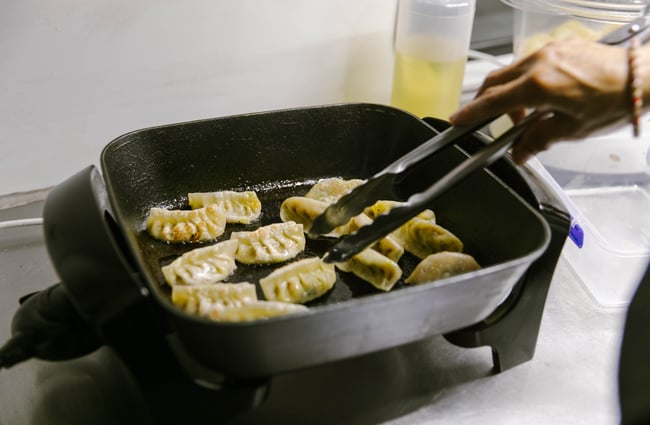 Pan frying dumplings inside Kung Fu Dumplings food truck.