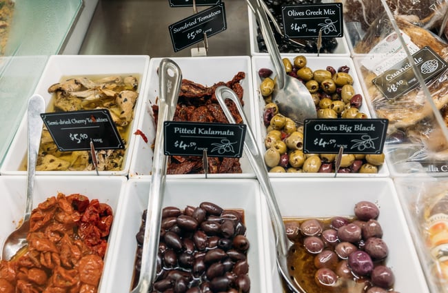 A close up of olives in a deli counter.