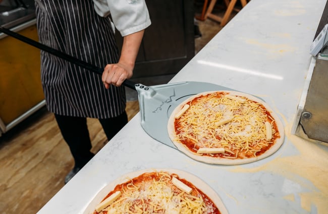 A close up some one scooping up a pizza.