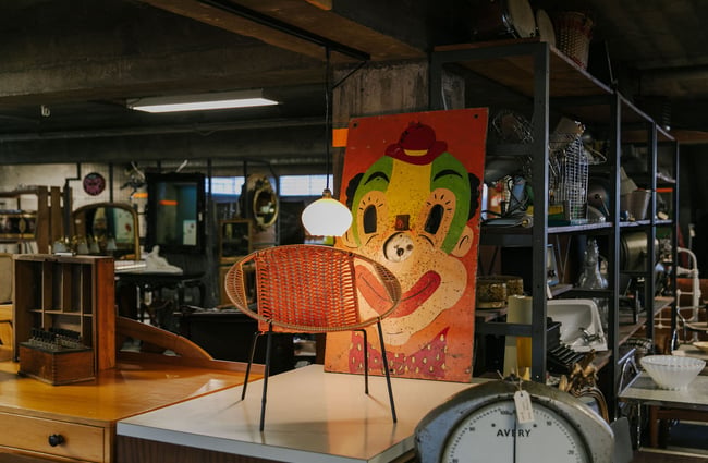 Vintage chair with retro painting of clown's face behind it at La Voute, Christchurch.