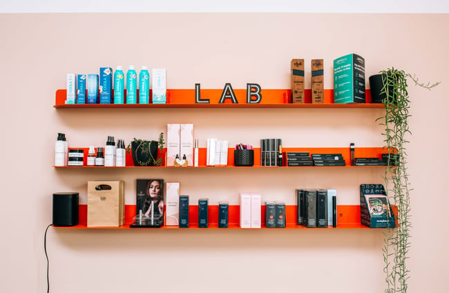 Close up of skin products on display on red shelves.