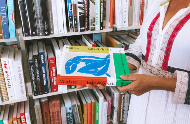 Woman holding a book about artist, Matisse, at Lamplight Books, Auckland.