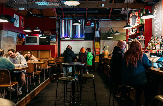 People sitting at tables, up at the bar and standing at high tables inside Last Place Bar.
