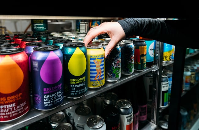 Close up of a hand reaching for a can of craft beer in the fridge at Last Place Bar.
