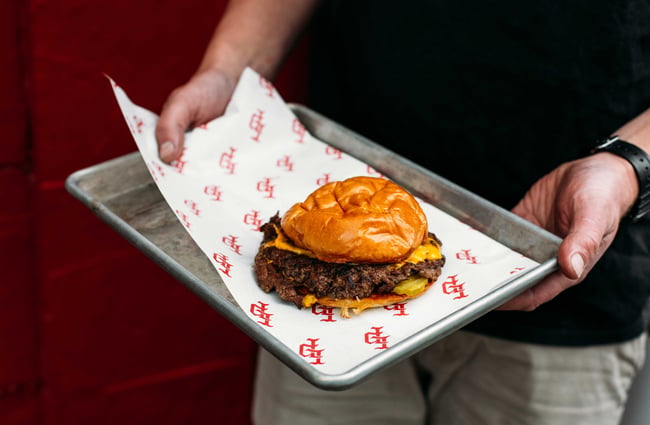 Close up of a man holding a burger on a tray at Last Place Bar.