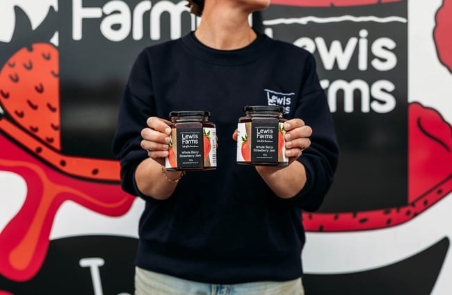 Staff member holding two jars of preserves at Lewis Farms.