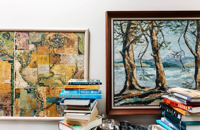 Paintings on the wall and a stack of books at Liberty Books.