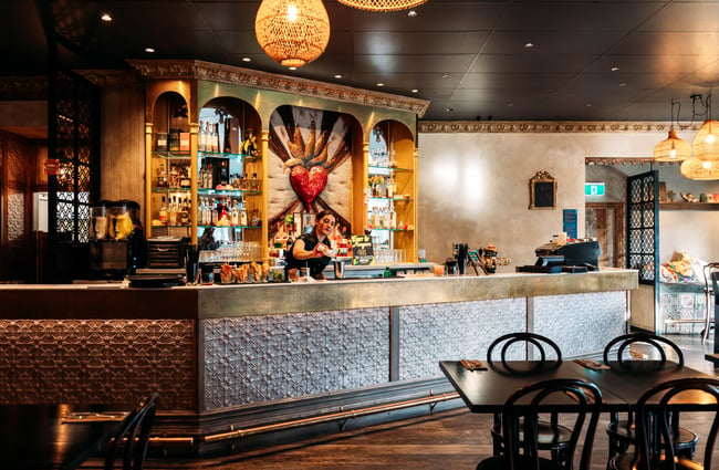 Bar area in the background with tables and chairs in the foreground at Libre.