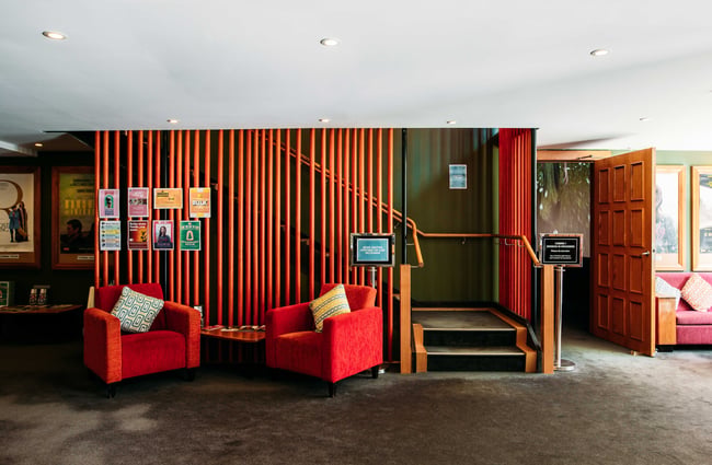 Red chairs next to a staircase leading to a cinema.