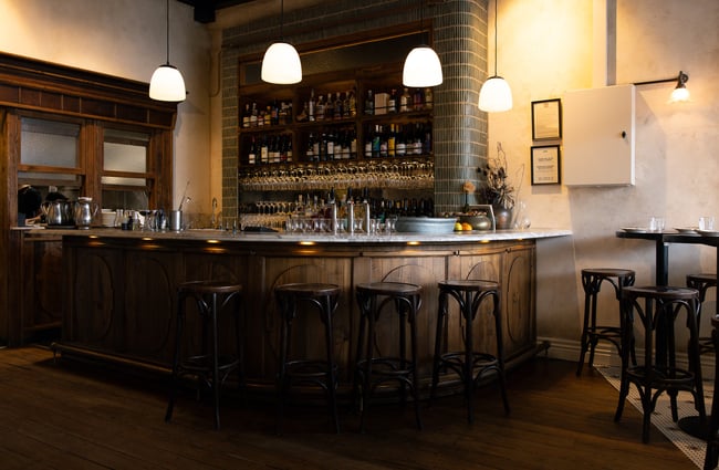 A grand wooden bar inside a dimly lit restaurant.