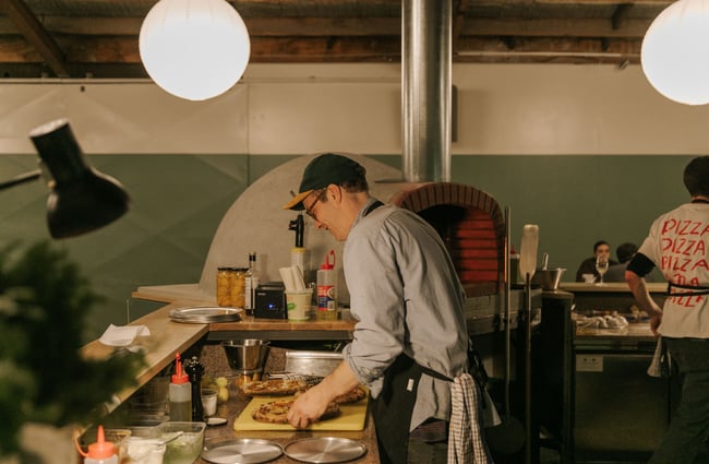 A man making pizza behind the bar at Lillies Christchurch.