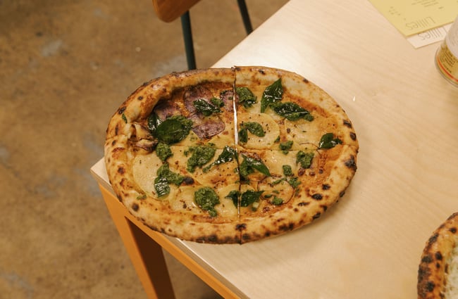 A pizza sitting on the corner of a table.