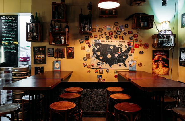 A poster of a map, beer label stickers and beer crates adorning a wall inside Little Beer Quarter.