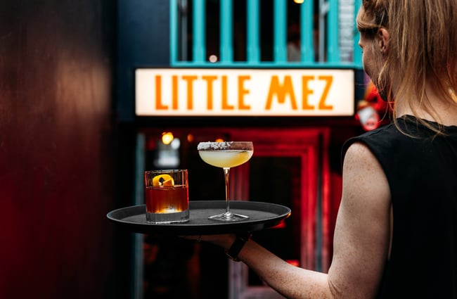Two drinks on a tray being held by a wait staff.
