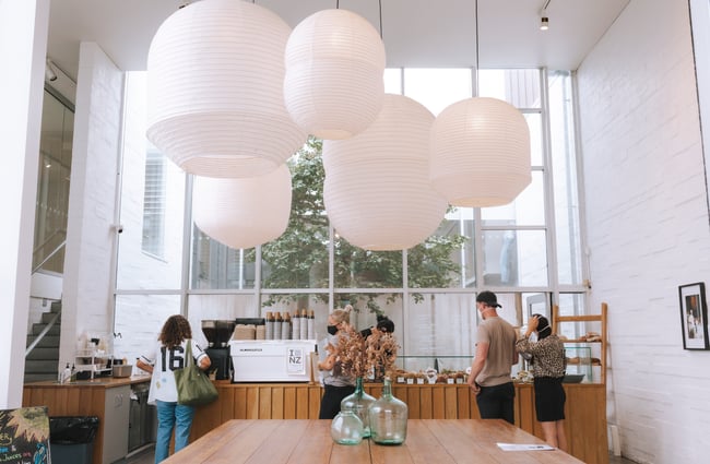 Large wooden tables with pendant paper lanterns above at Little Rosie, Auckland.
