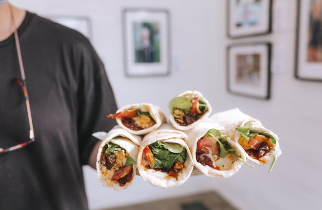 Person holding a tray of breakfast wraps from Little Rosie, Auckland.