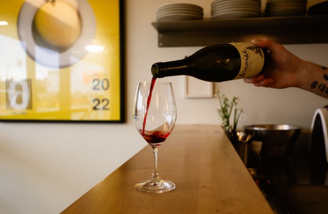 A glass of red wine being poured.