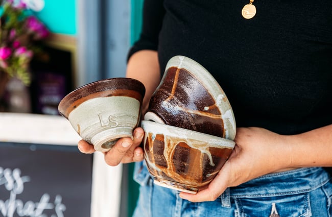 Person holding a collection of ceramic cups outside Love Stomp.