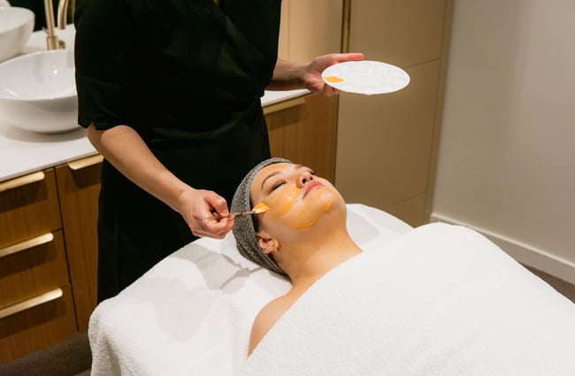 A cream being applied to a customer's face with a brush.