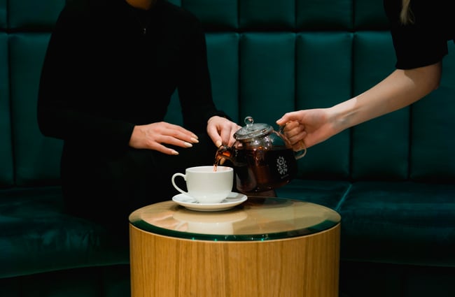 A close up of tea being poured into a tea cup.