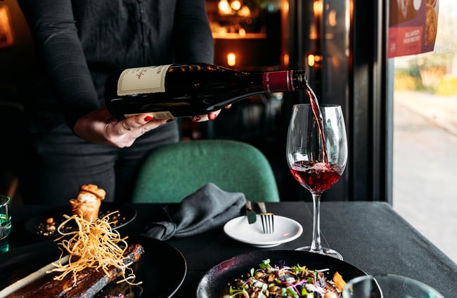Staff member is pouring a glass of red wine at Lustre.