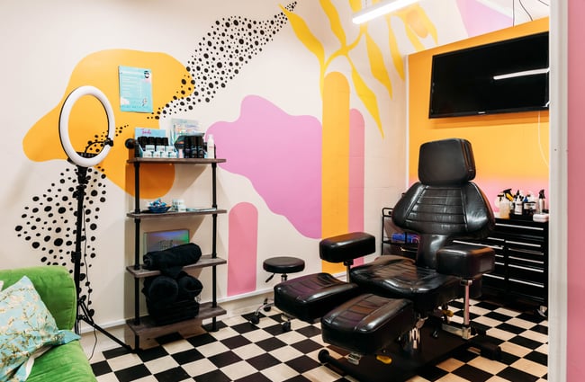 Tattoo studio room with black leather chair and a bright wall mural