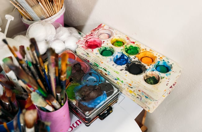 Close up of used paint brushes and colourful paint palettes
