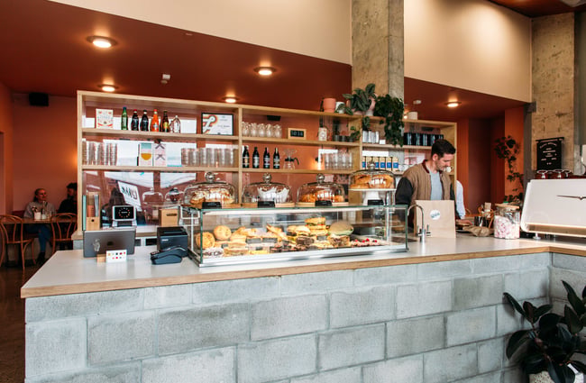 A male staff member working behind the salmon coloured counter at Lykke cafe Hamilton.