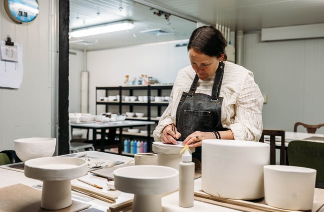 Ceramicist in the workshop at Mabel Vickers working on a piece of pottery.