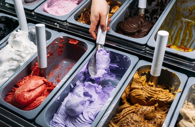 Colourful gelato in a display fridge being scooped up.