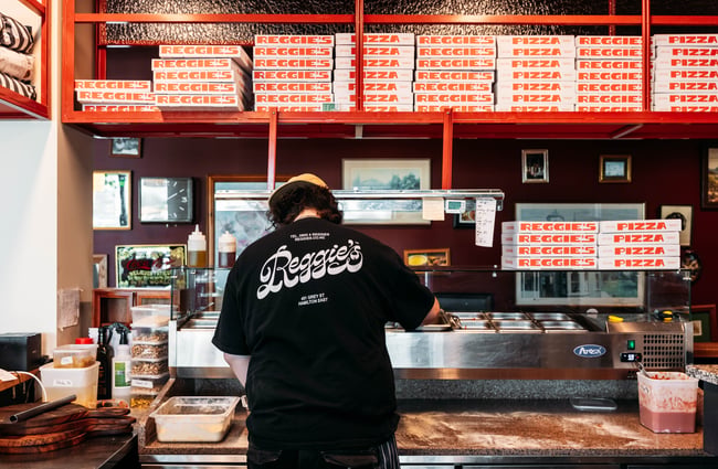 A man with his back to the camera is making a pizza in a restaurant at Made.