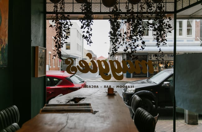 A darkly lit view of a grey Dunedin street from inside Maggies.