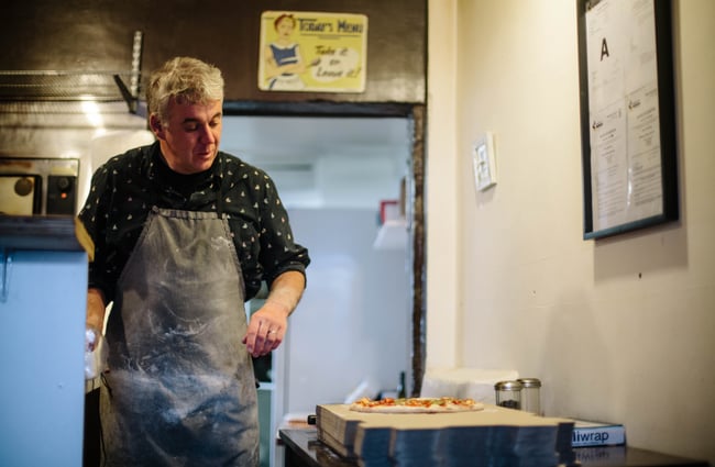A chef looks at a freshly made pizza.