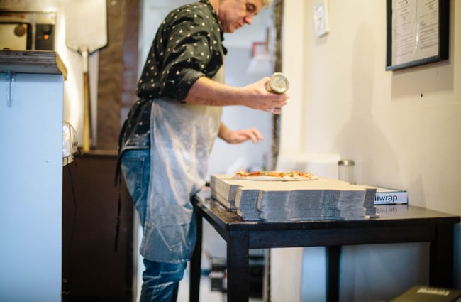 Staff member making a pizza.