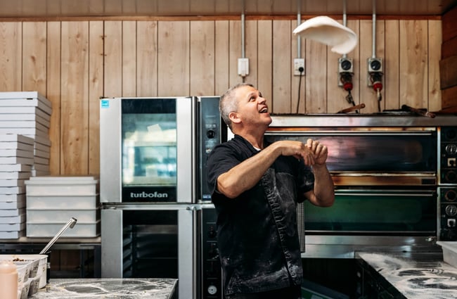 Chef flipping pizza dough in Manakau Market.