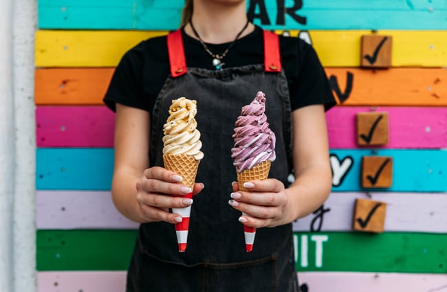 Shop assistant holding two real fruit ice creams outside Manakau Market.