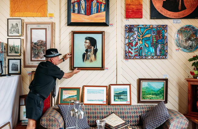 A man adjusting a painting on a wall at Mangaweka Gallery in Rangitikei.