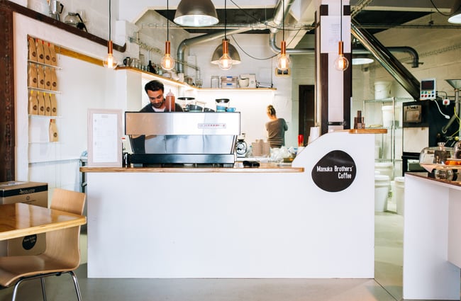Barista busy behind counter at Manuka Brothers, Hamilton.