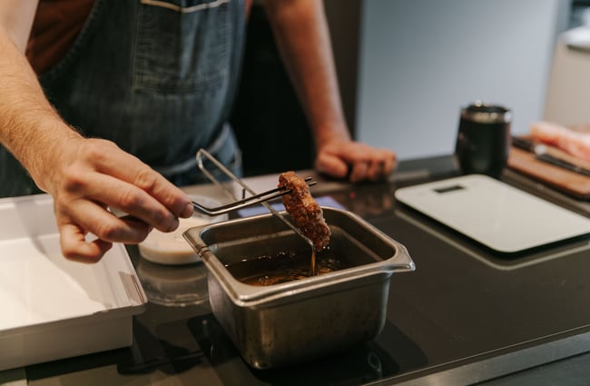 A close up of a piece of meat being dipped.