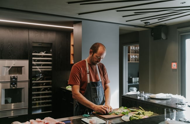 Giulio Sturla standing in his kitchen slicing fish.