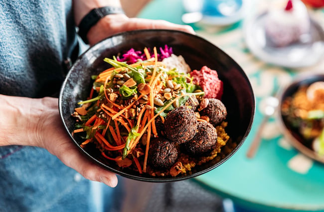 Close up of falafel bowl at Worker placing bowl of food on table at Maranui Cafe in Lyall Bay Wellington
