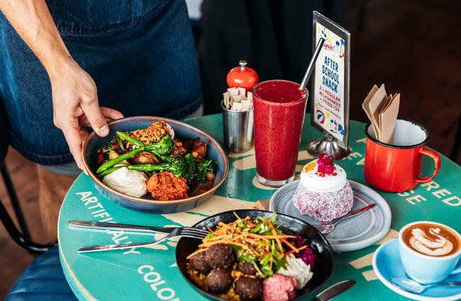 Worker placing bowl of food on table at Maranui Cafe in Lyall Bay Wellington