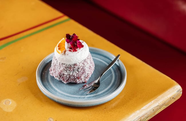 Pink Lamington on table at Worker placing bowl of food on table at Maranui Cafe in Lyall Bay Wellington
