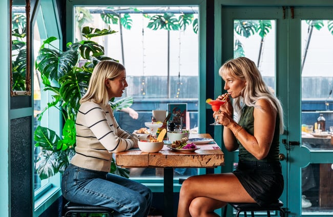 Two women dining around a table.